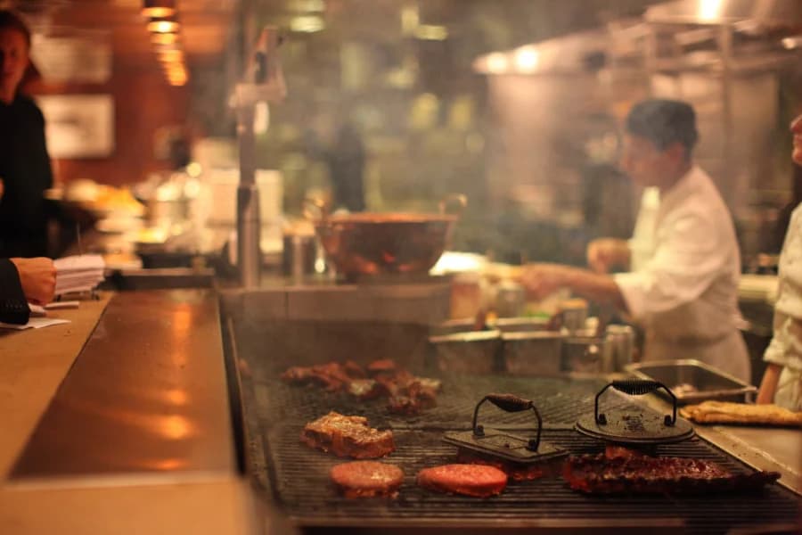 Des pièces de viande cuisent sur la plancha d'une cuisine de restaurant